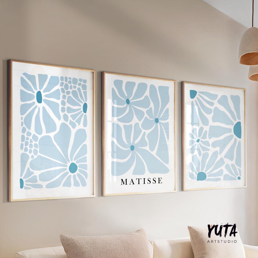 Trio of abstract blue botanical prints in light wood frames arranged above a sofa.