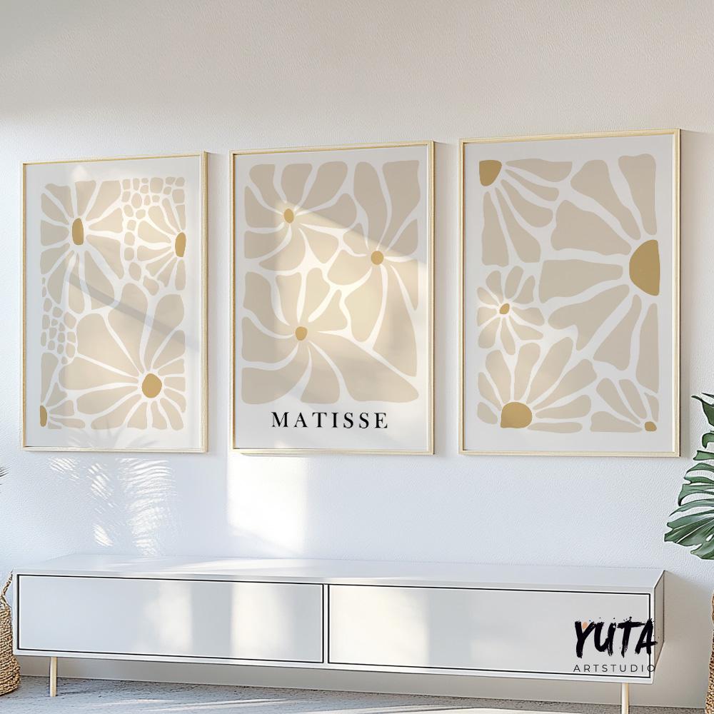 Minimalist beige floral triptych in gold frames displayed above a modern white sofa.