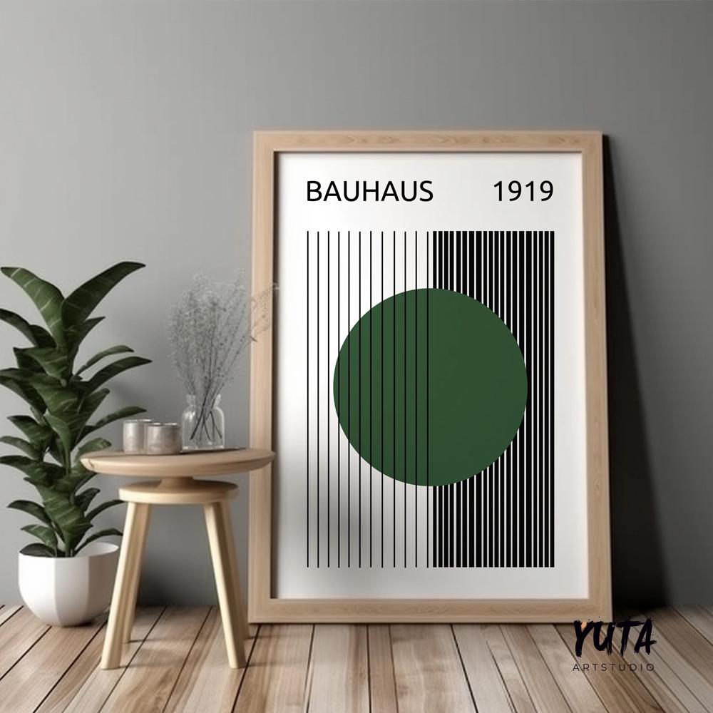 Framed Bauhaus print with dark green circle and black lines, styled beside potted plant and ceramics.