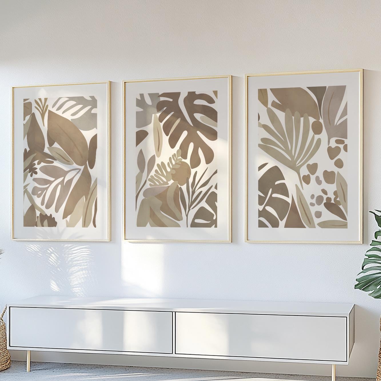 Three minimalist mocha tropical prints in gold frames arranged above a modern console