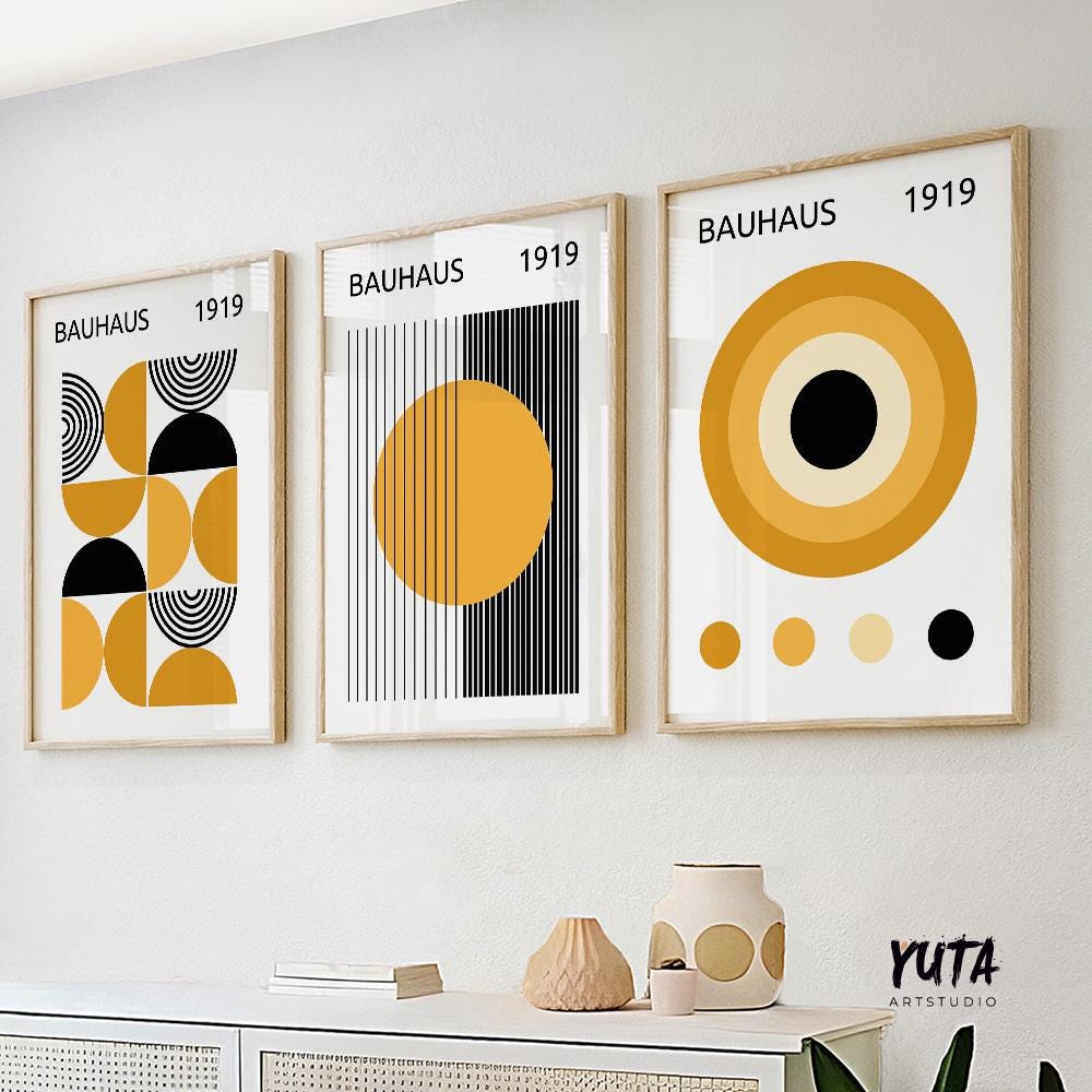 Three framed Bauhaus abstract prints in mustard yellow and black, displayed above a sideboard in natural daylight.