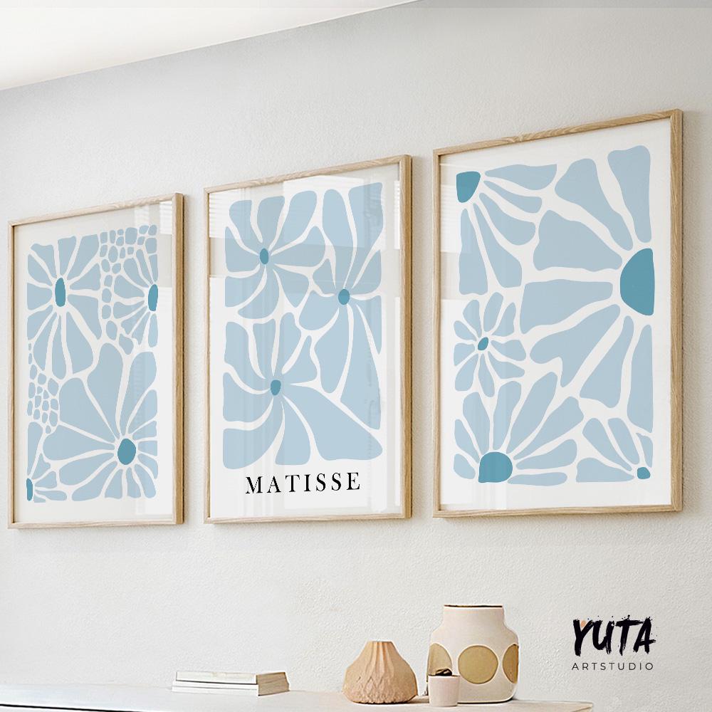 Three abstract blue botanical prints in light wood frames, arranged above a white console