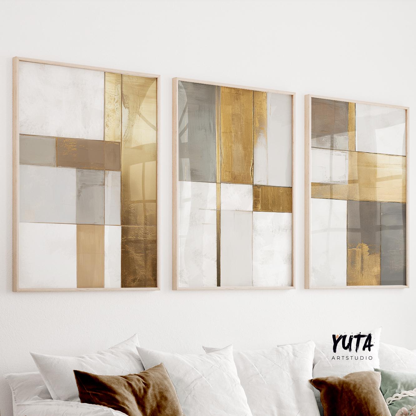 Geometric abstract triptych in gold and neutral tones, framed above a white sofa with plush pillows.