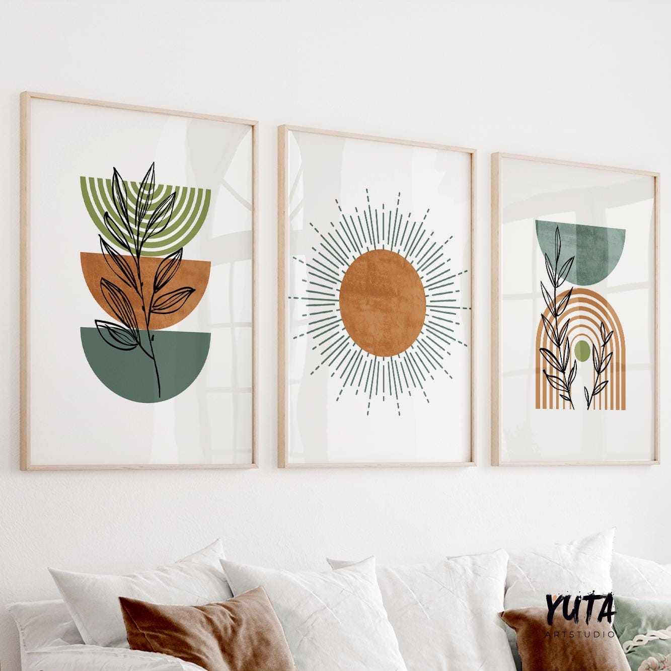 Three framed boho prints with modern botanical and sunburst motifs above pillows for scale