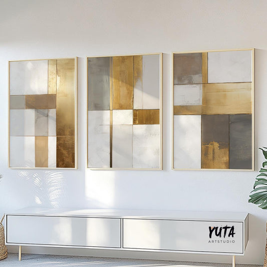 Three-piece geometric abstract art set in gold and neutral tones with visible print sizes above a console