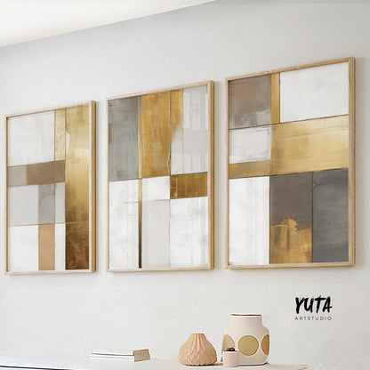 Three-panel abstract artwork in gold, beige, and white tones, framed and lit by daylight