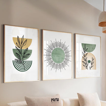 Abstract botanical and sunburst prints in light wood frames arranged above a beige sofa