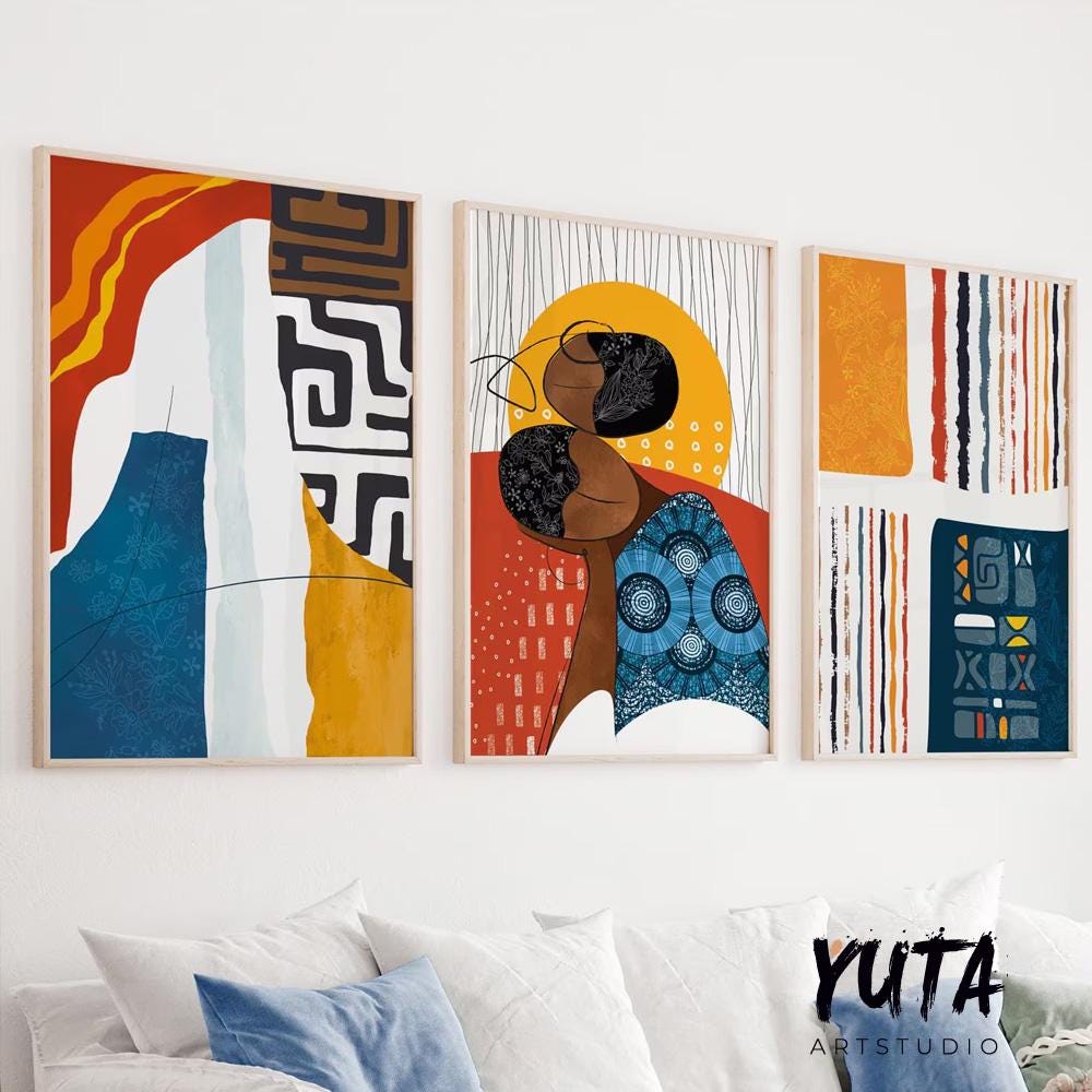 Abstract African-inspired prints in light wood frames arranged above a white sofa.
