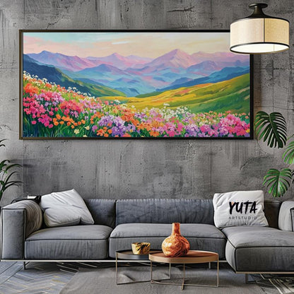 Framed panoramic mountain landscape with vibrant wildflowers centered above a modern sofa