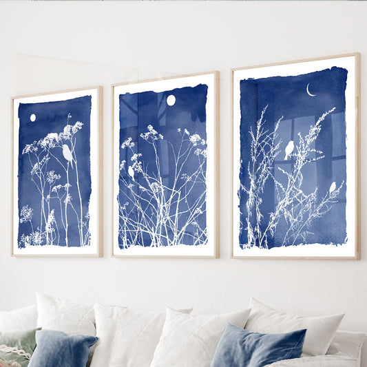 Blue botanical wall art set of 3 featuring wildflowers and perched birds on rich navy blue backgrounds