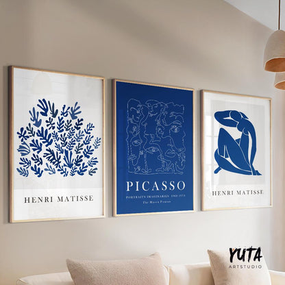 Three framed abstract navy blue art prints displayed above a beige sofa in natural light