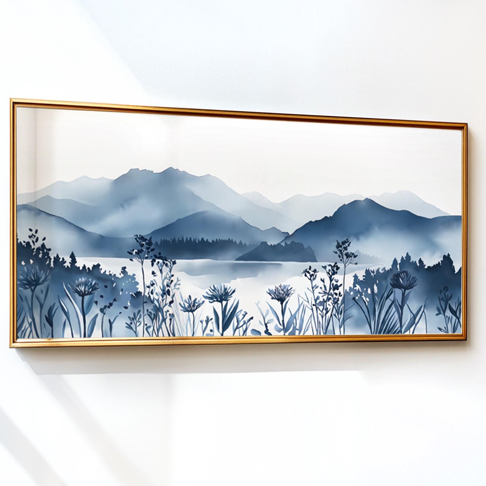 Navy blue mountain landscape print with wildflowers in a gold frame on a white wall
