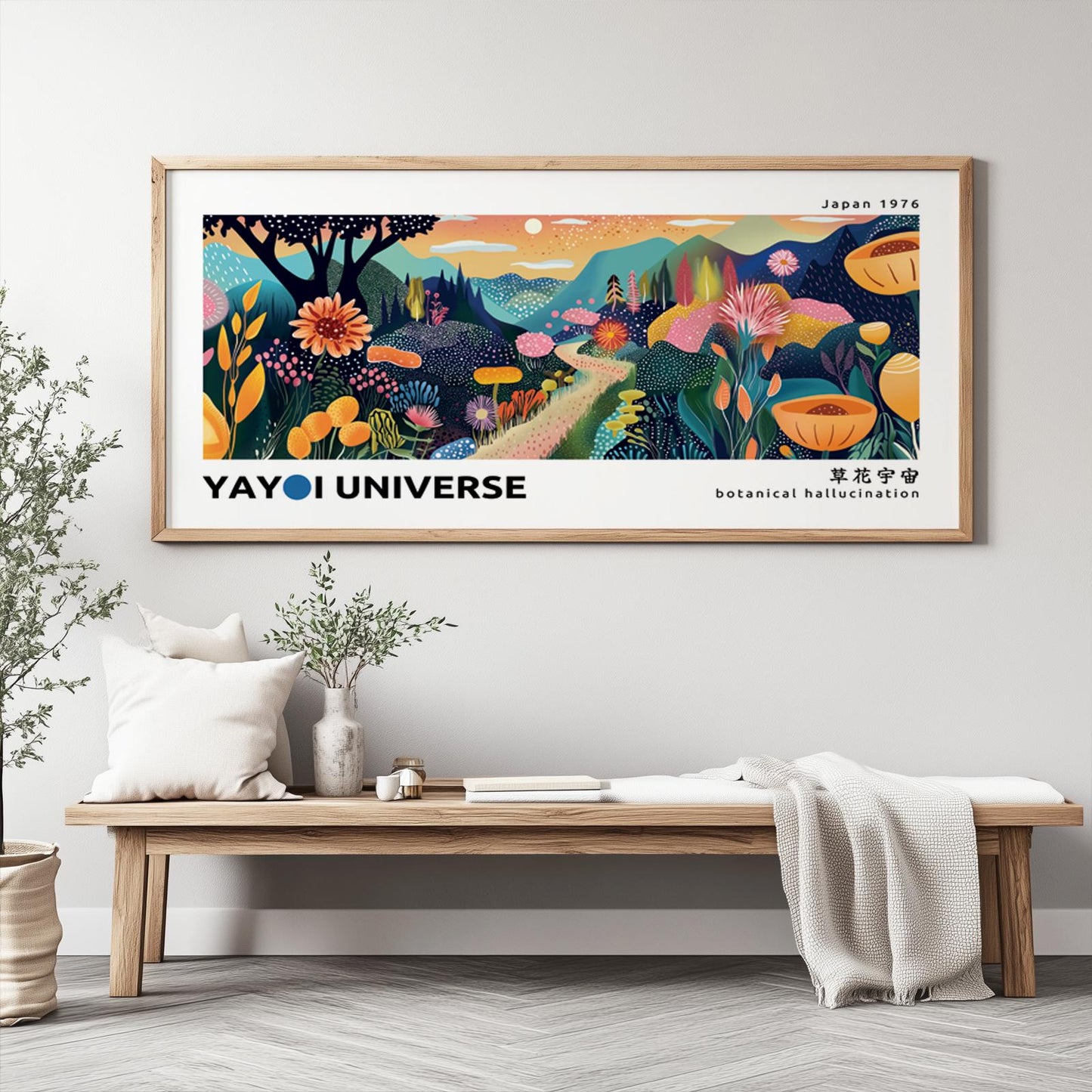Colorful abstract mountain print with dotted floral patterns in a light wood frame above a bench with plants and ceramics.