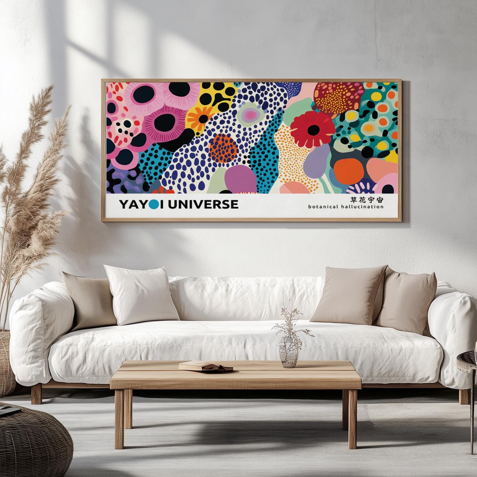 Framed abstract floral artwork with bold colors displayed above a minimalist coffee table with books and dried plants.