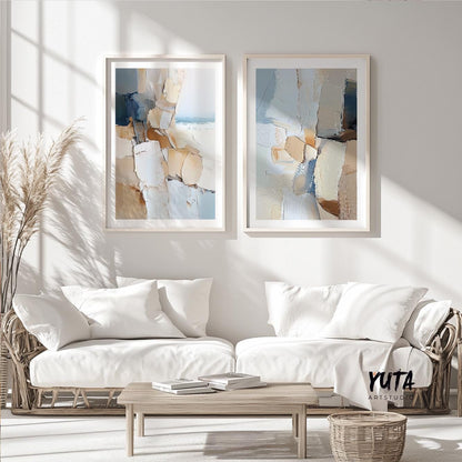 Neutral abstract diptych in light wood frames arranged above white seating area