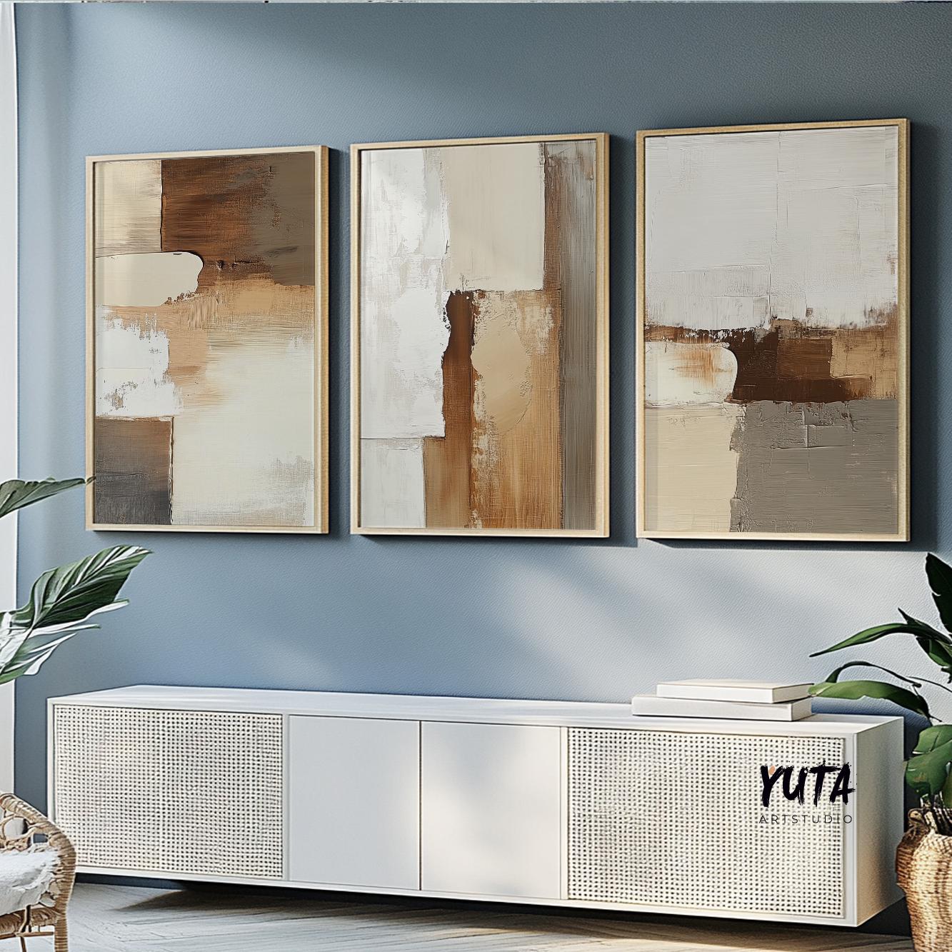 Abstract earth tone paintings in light wood frames displayed as a triptych above a console