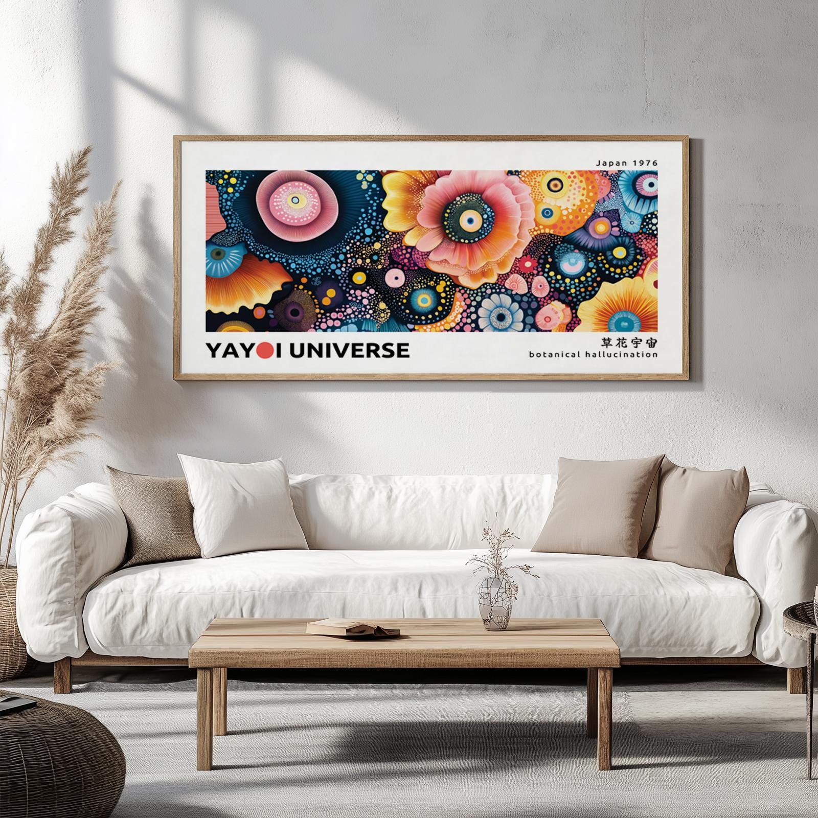 Framed botanical flower art in vivid colors styled above a sofa with pampas grass and books.