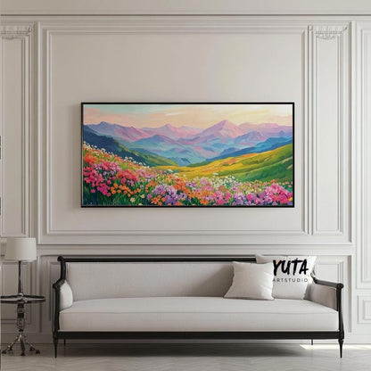 Framed panoramic mountain landscape with vibrant wildflowers hung above a classic sofa.