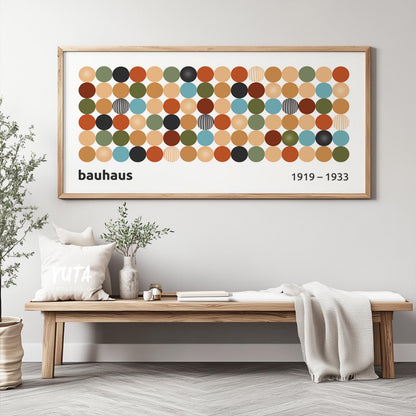 Framed Bauhaus geometric print with colored circles displayed above a wooden bench in daylight
