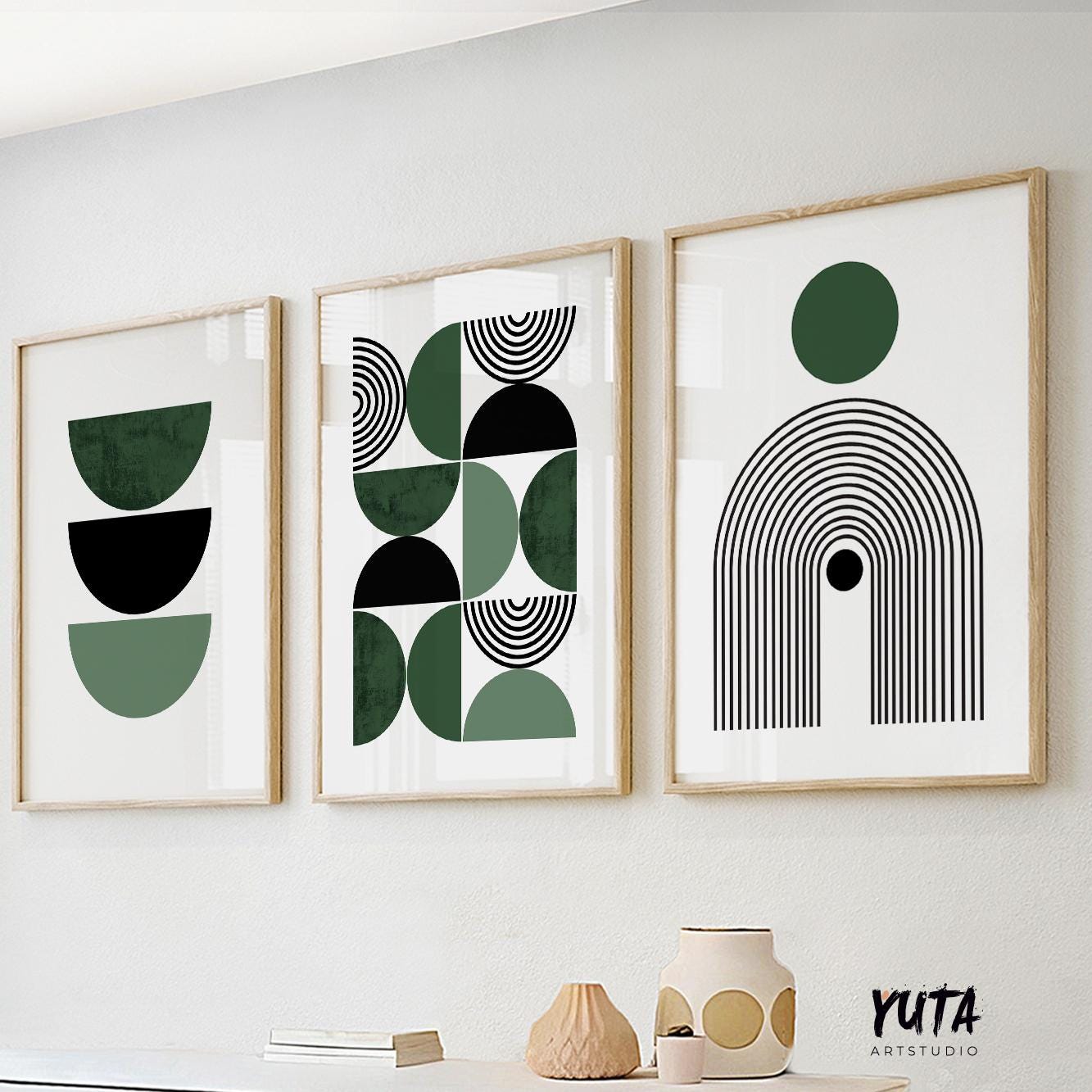 Framed Bauhaus-inspired geometric prints in a trio above books and ceramic vases.