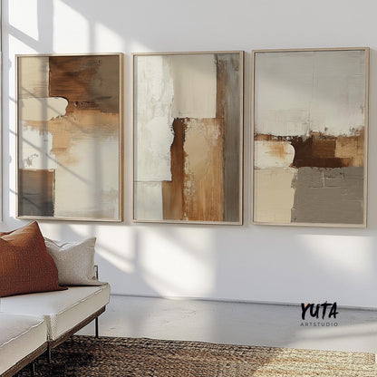 Three-piece neutral abstract wall art set in wood frames, sunlit above a cream sofa
