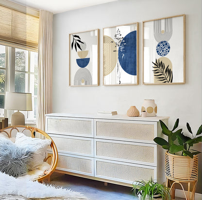 Geometric abstract art prints in navy and beige, framed in light wood above a white sideboard