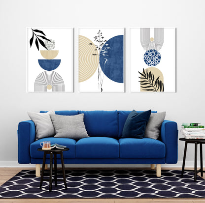 Three framed geometric botanical prints in navy and beige above a blue sofa with styled books