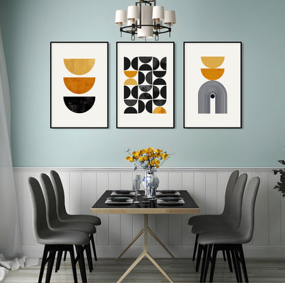Three framed mustard yellow and black geometric prints above a dining table with flowers