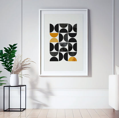 Framed geometric print with mustard yellow and black shapes displayed in natural light