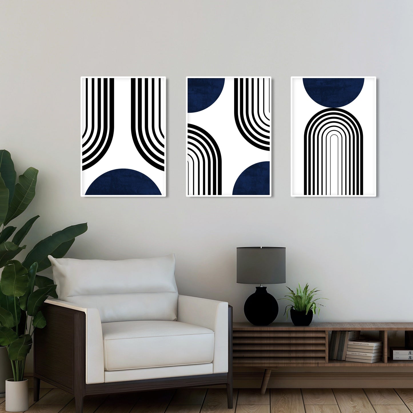 Three framed abstract navy blue and black prints hung above a modern white armchair
