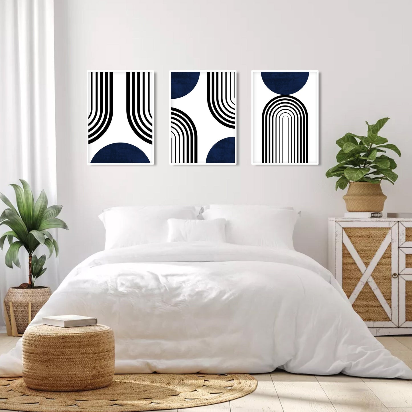 Three abstract navy and black prints in a mid-century style above a sunlit bed