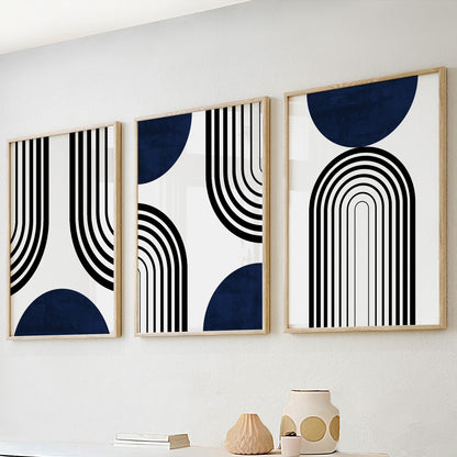 Framed navy blue and black abstract prints in three sizes displayed above a console.