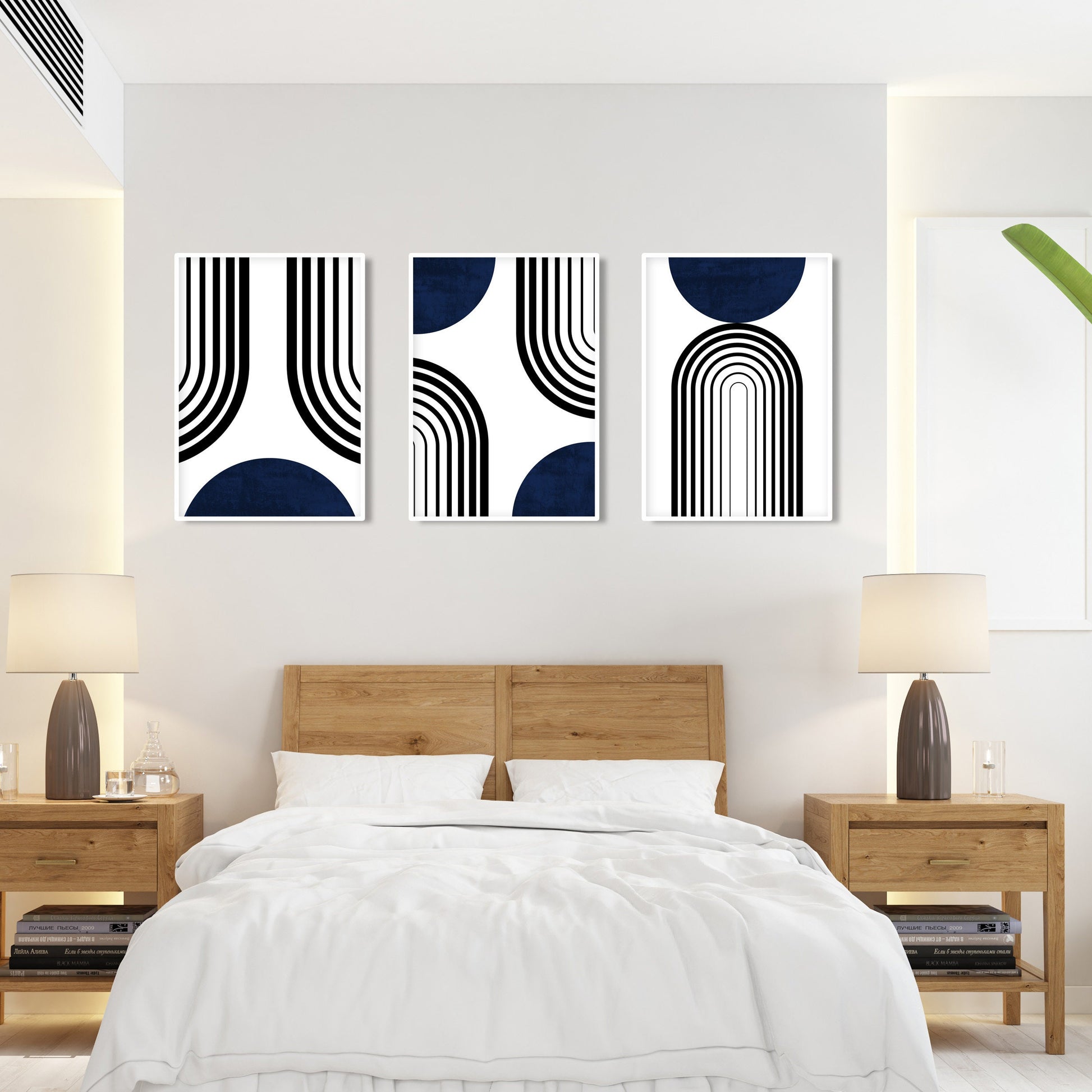 Set of three framed abstract navy blue and black prints arranged above a bed.