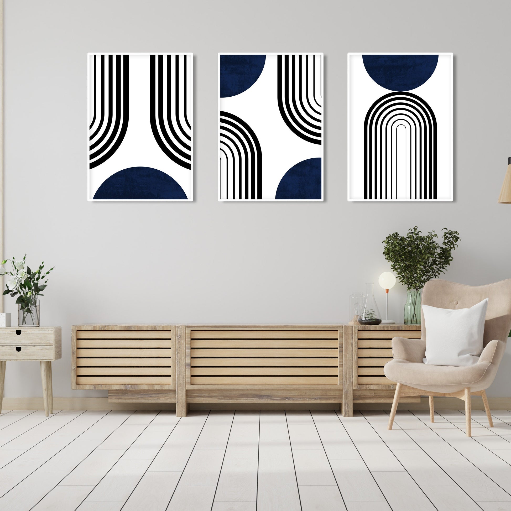Three framed abstract navy and black prints arranged above a console with plants and ceramics