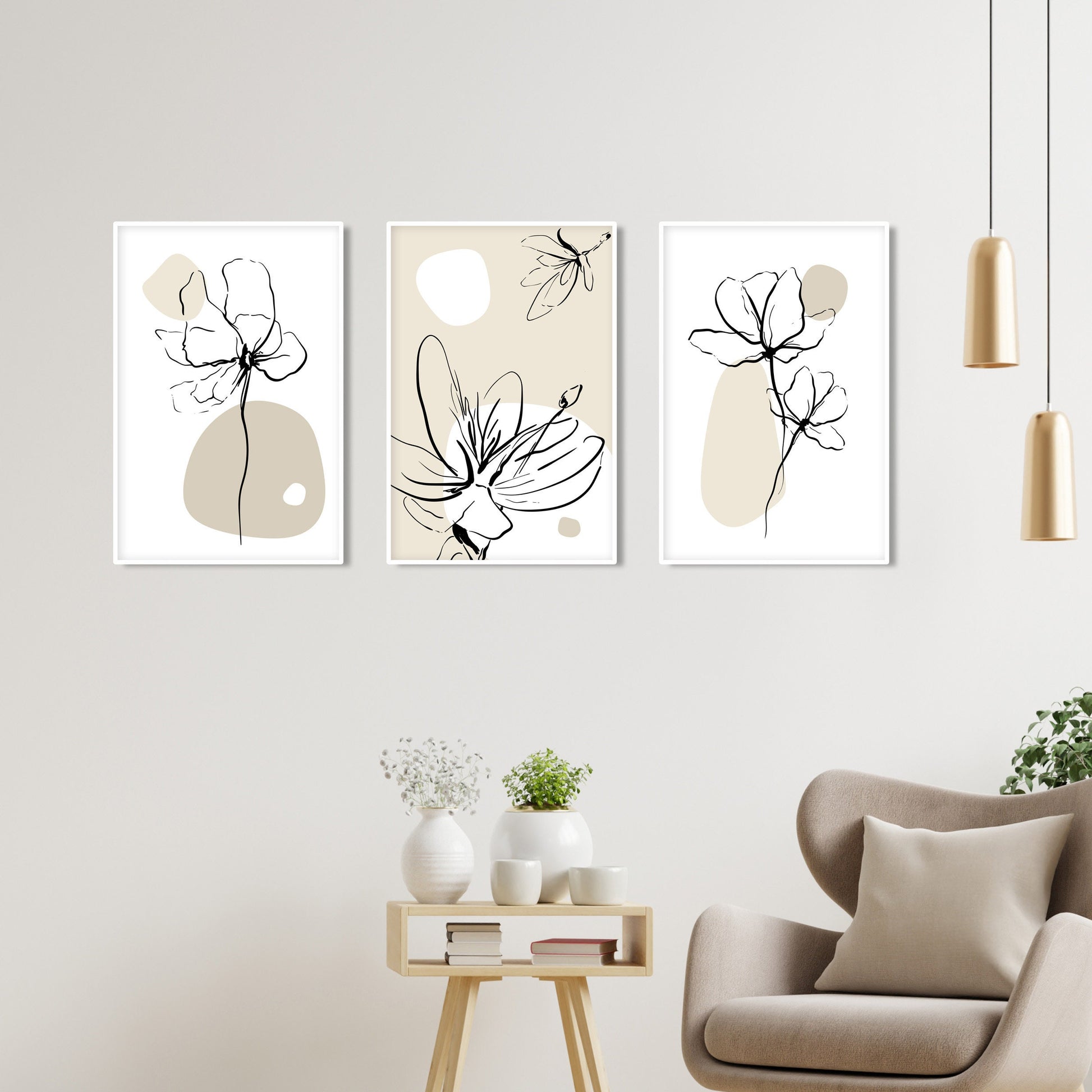 Three minimalist botanical prints in white frames hung in a row above a beige chair