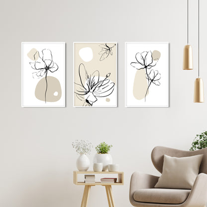 Three minimalist botanical prints in white frames hung in a row above a beige chair