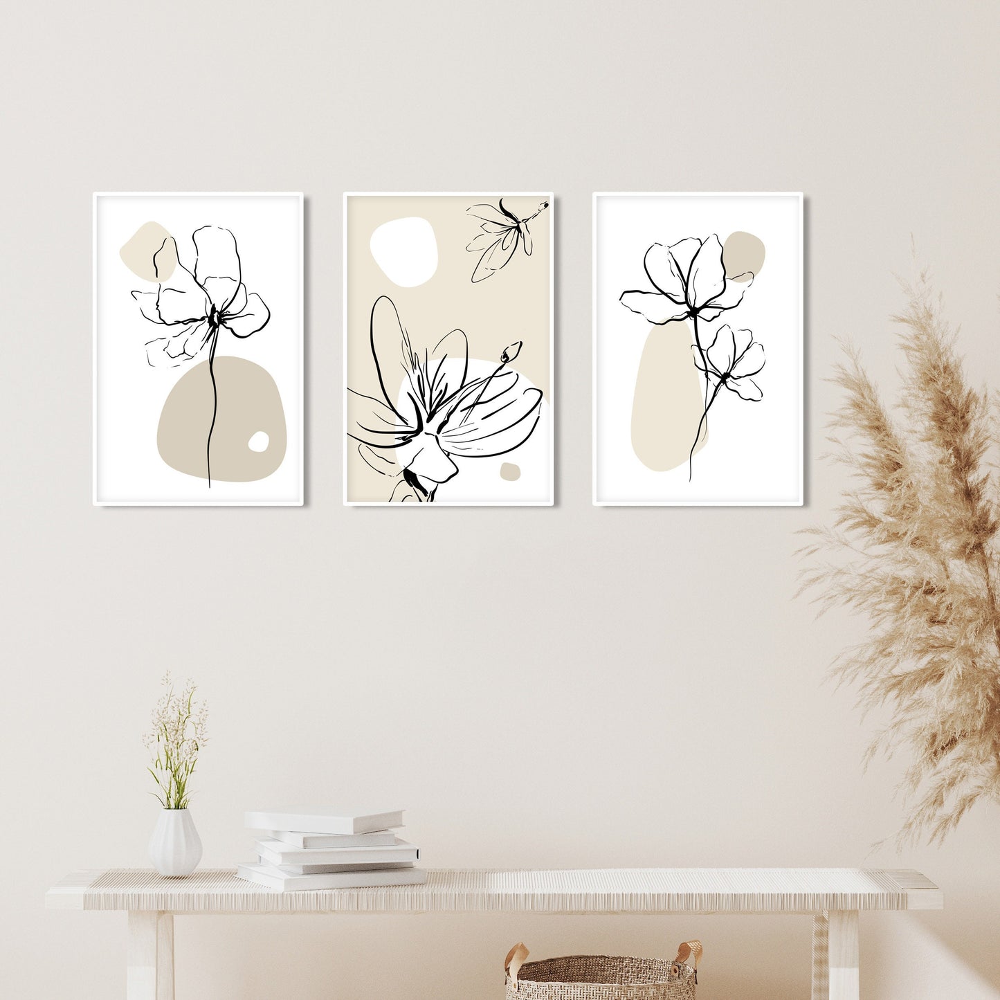 Three boho floral line art prints in white frames above a light wood console