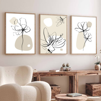 Trio of minimalist beige floral line art prints in wood frames above a wooden console