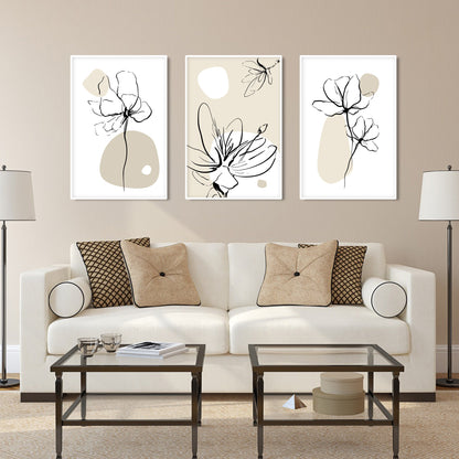 Boho floral line art trio in white frames arranged above a beige sofa