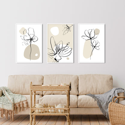 Three framed boho floral line art prints with neutral beige accents above a cream sofa