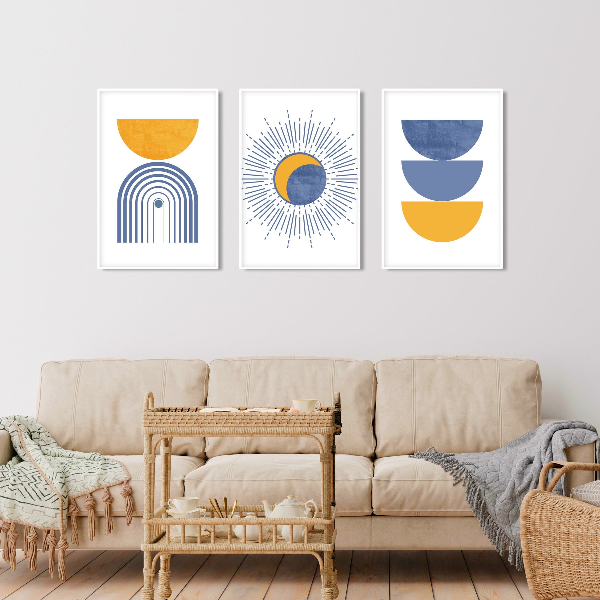 Three abstract boho prints in light blue and mustard, framed above a cream sofa