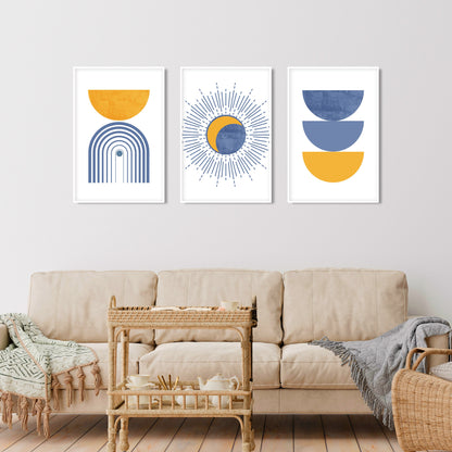 Three abstract boho prints in light blue and mustard, framed above a cream sofa