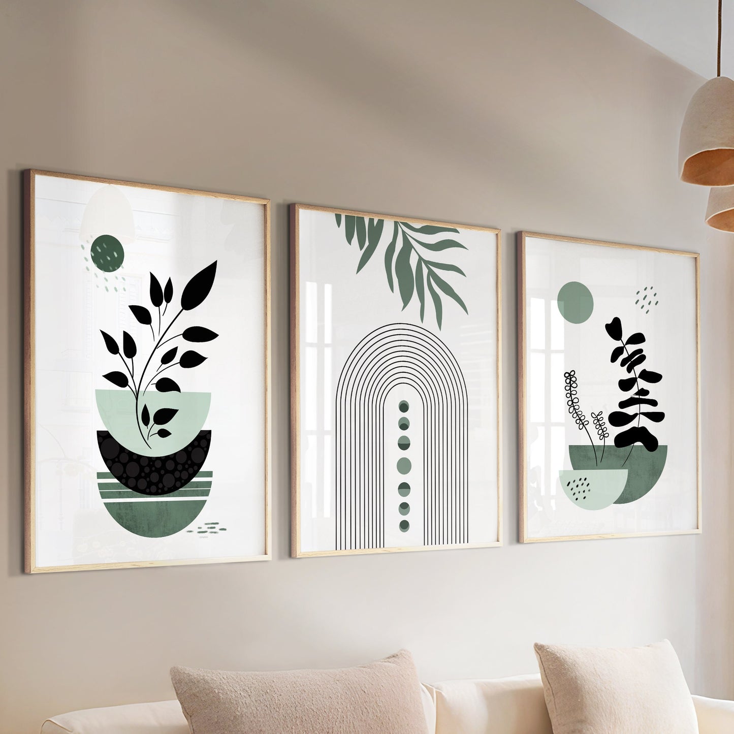 Three-piece sage green boho wall art set in light wood frames above a cream sofa