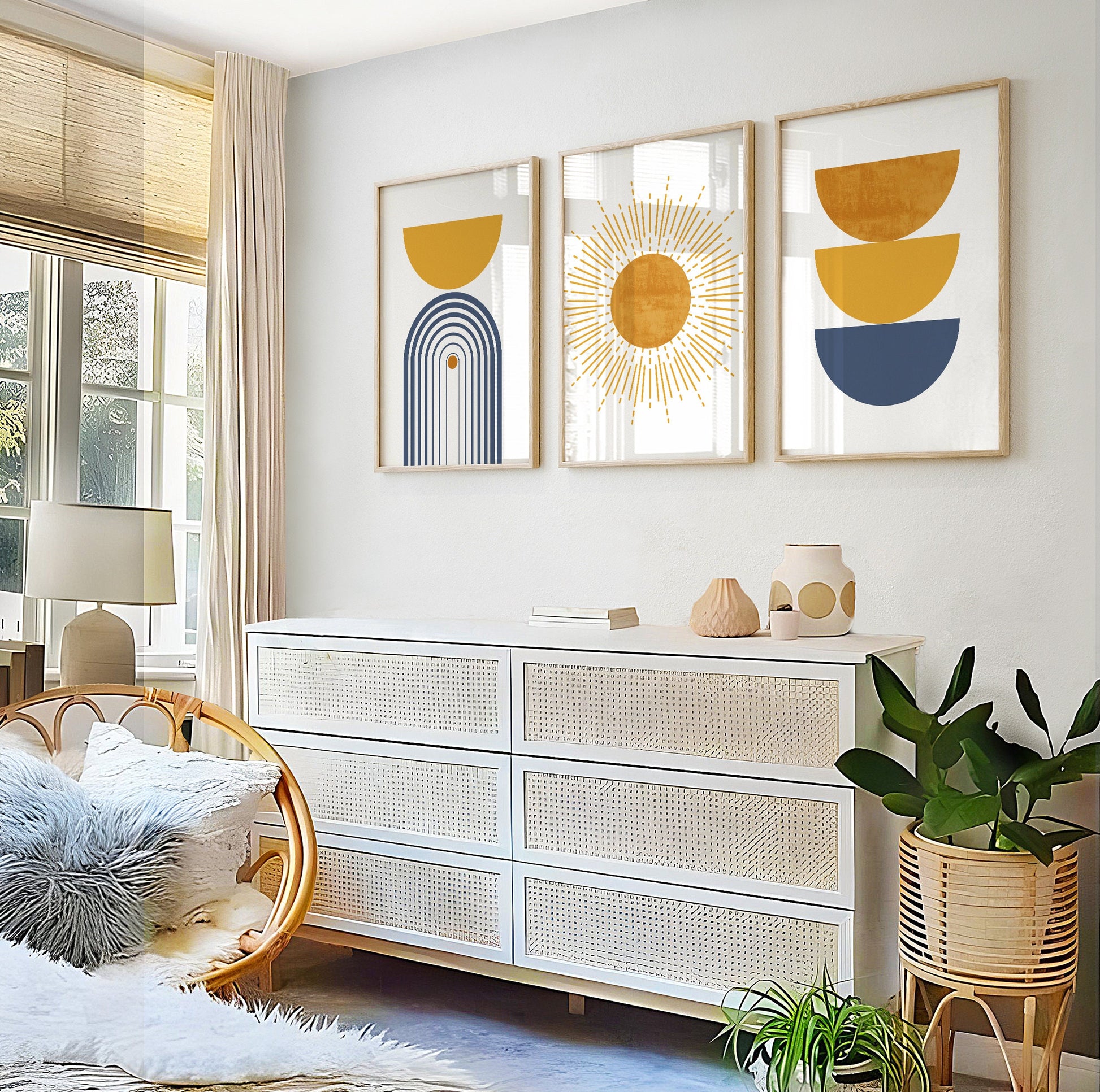 Three framed modern boho prints in blue and mustard above a rattan lounge chair