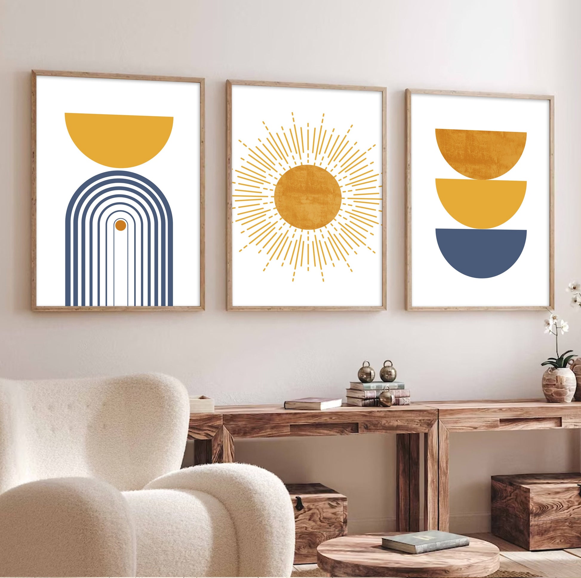 Three framed abstract prints in mustard and blue arranged above a wooden console in daylight
