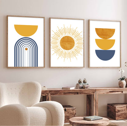 Three framed abstract prints in mustard and blue arranged above a wooden console in daylight