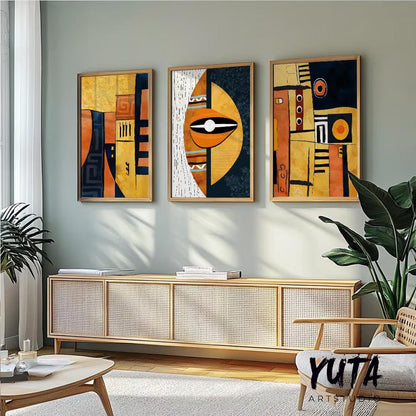 Geometric African abstract art triptych in wood frames above a sideboard with plants and books