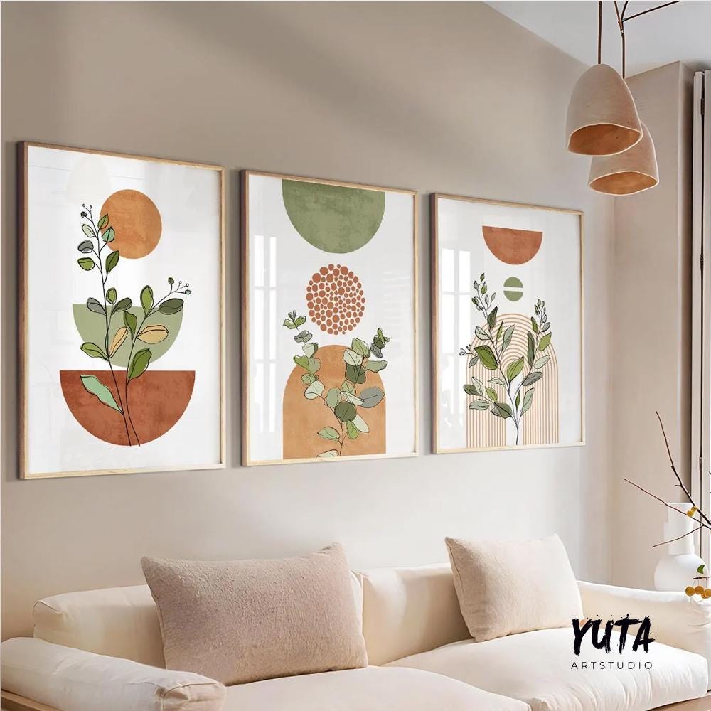 Trio of framed terracotta and sage botanical prints above a cream sofa in natural light