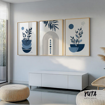 Three navy blue boho art prints in gold frames displayed above a low white cabinet in soft daylight