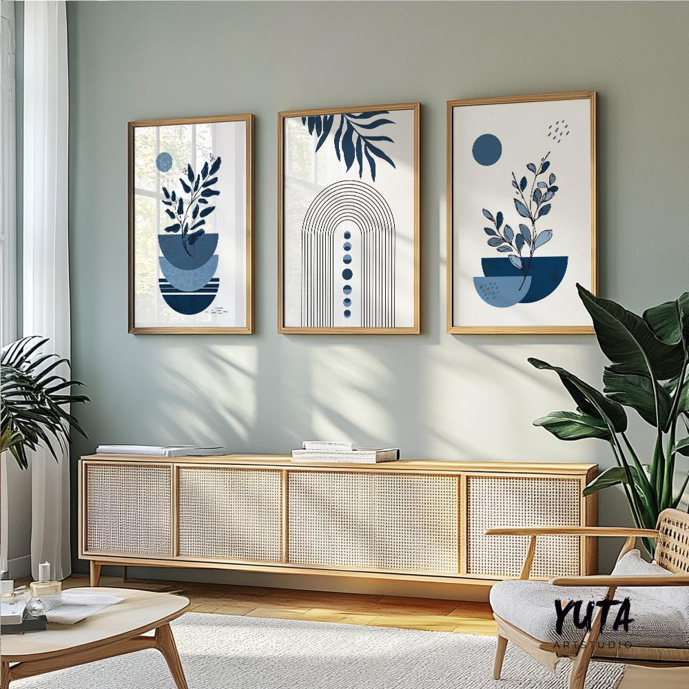Trio of framed abstract navy blue botanical prints above a light wood console with stacked books
